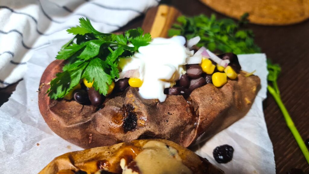 Close-up of vegan stuffed sweet potatoes loaded with black beans, corn, onions, and fresh cilantro.