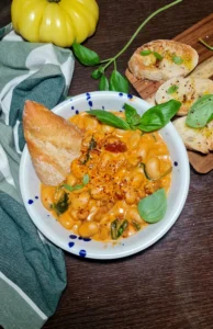 A detailed view of a bowl filled with Merry me beans, showing the creamy orange sauce, white beans, spinach, and sun-dried tomatoes.