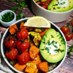Detailed overhead look at a fresh roasted vegetable quinoa bowl featuring sweet potatoes, zucchini, and an avocado.