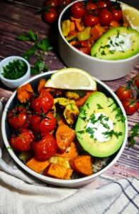 Detailed overhead look at a fresh roasted vegetable quinoa bowl featuring sweet potatoes, zucchini, and an avocado.