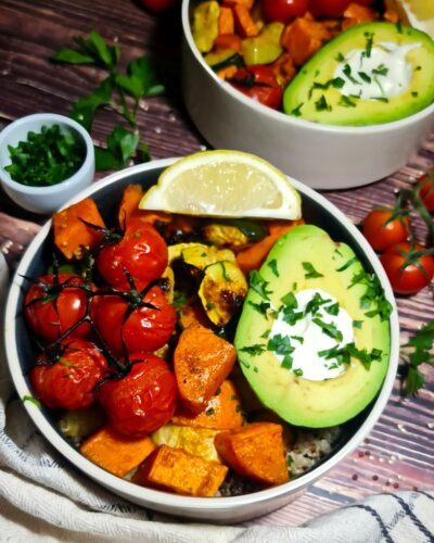 Detailed overhead look at a fresh roasted vegetable quinoa bowl featuring sweet potatoes, zucchini, and an avocado.