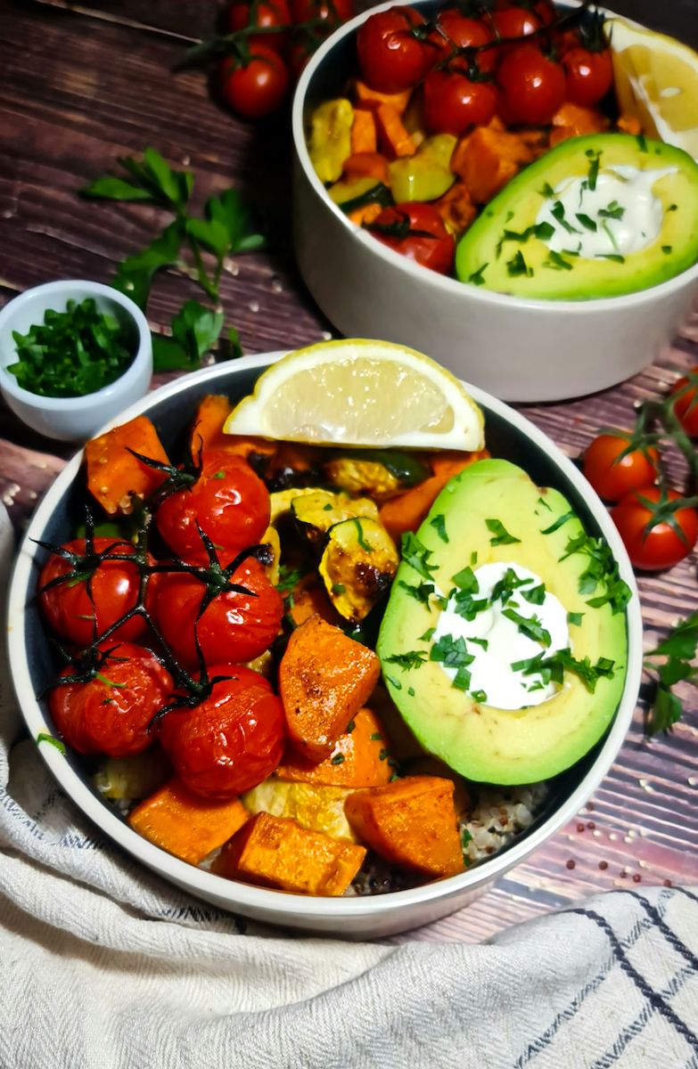 Detailed overhead look at a fresh roasted vegetable quinoa bowl featuring sweet potatoes, zucchini, and an avocado.