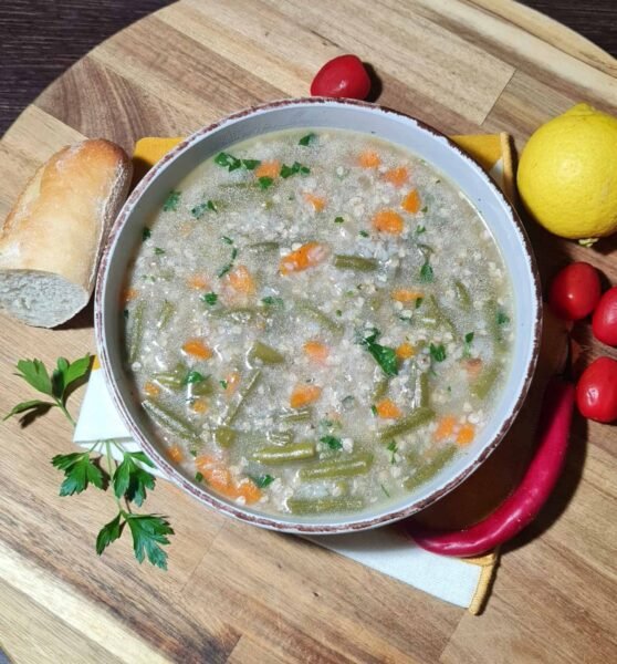vegan buckwheat and green bean soup served in a bowl with bread lemon and parsley