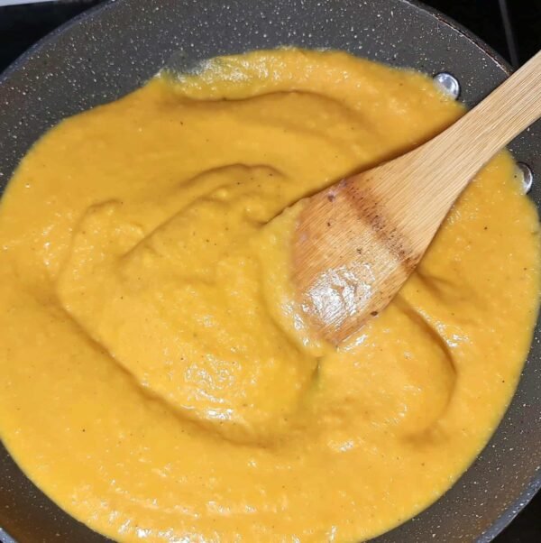 Close-up of pasta coated in creamy butternut squash sauce sprinkled with black pepper.