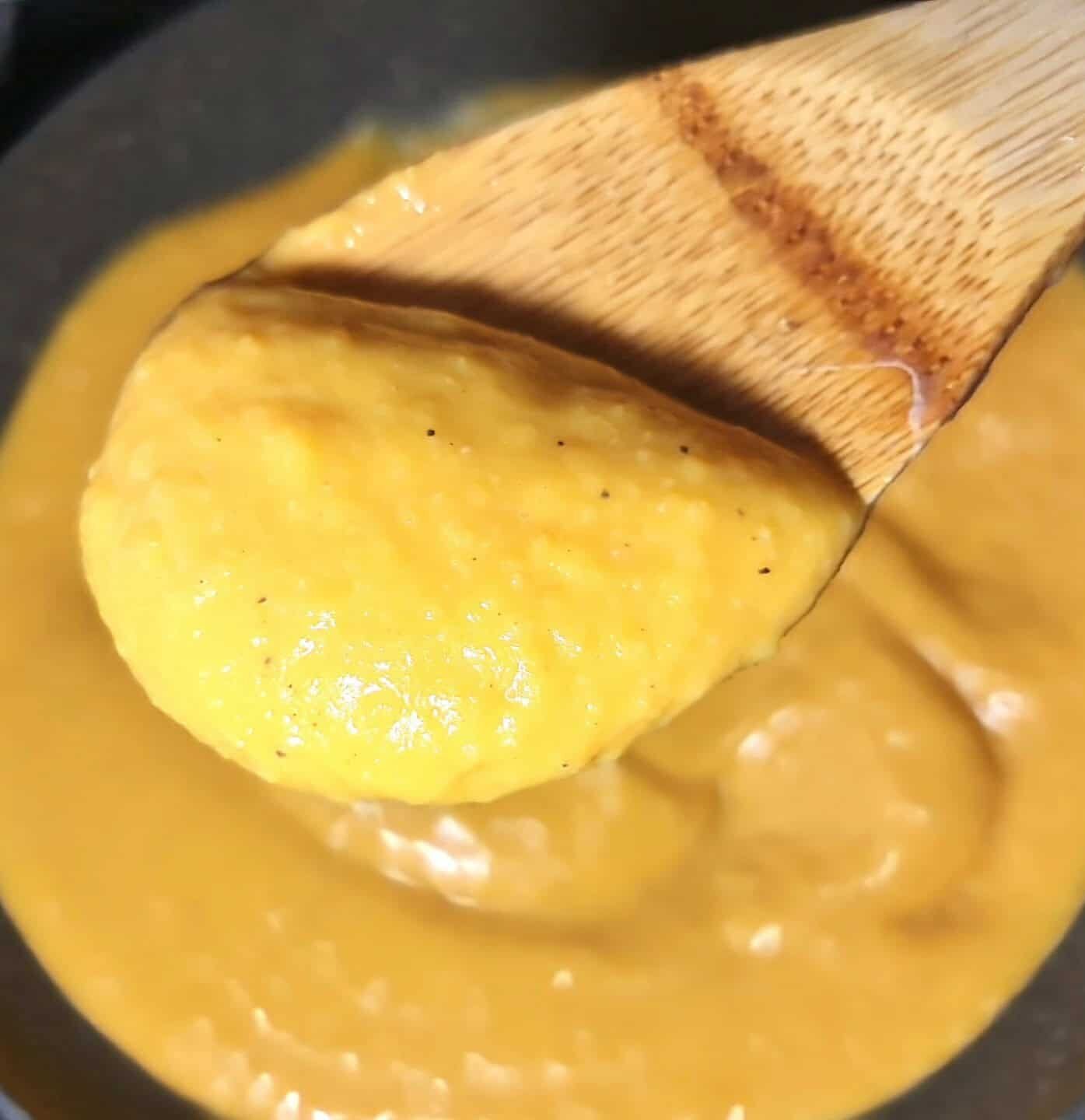 Butternut squash, garlic, onion, lemon, olive oil, and plant milk arranged on a table.