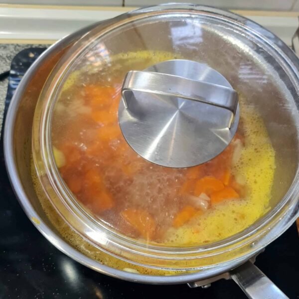 Carrot soup simmering in a pot with vegetable broth