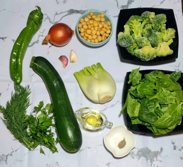Flatlay of zucchini, dill, spinach, fennel, chickpeas, and frozen broccoli arranged on a marble background.