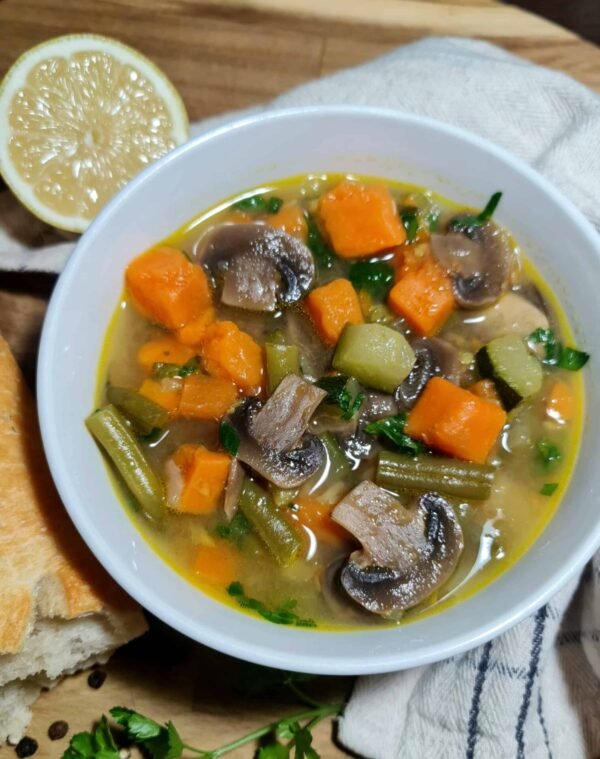 Close-up of easy vegetable soup showing chunks of sweet potato, mushrooms, zucchini, and green beans in a clear golden broth.