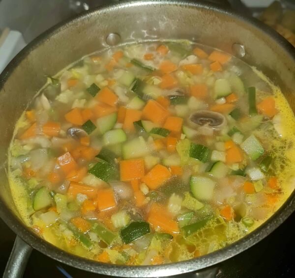 Vegetables simmering in a bubbling pot—zucchini, sweet potato, mushrooms, and green beans—for an easy vegetable soup.