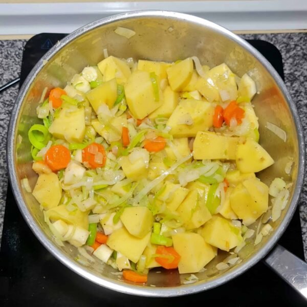 Chopped potatoes added to a pot of sautéed leeks, carrots, and celery before making Irish vegetable soup.