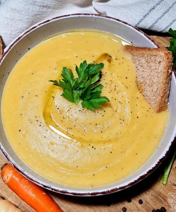 Close-up shot of a creamy bowl of Irish vegetable soup topped with parsley and served with bread.
