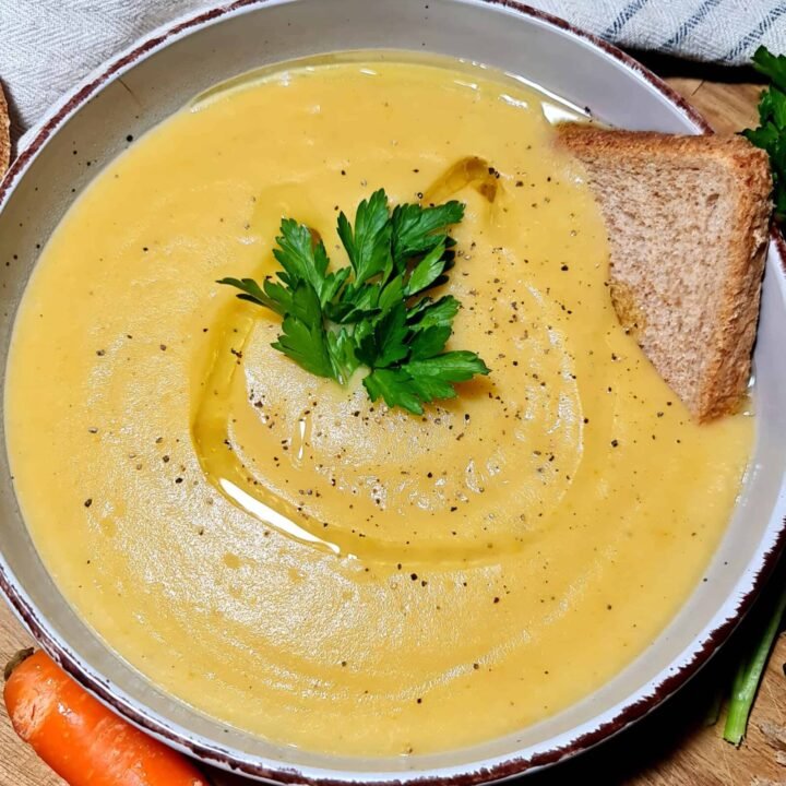 Close-up shot of a creamy bowl of Irish vegetable soup topped with parsley and served with bread.