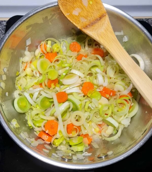 Pan of sautéed leeks, carrots, onions, and celery cooking for Irish vegetable soup.