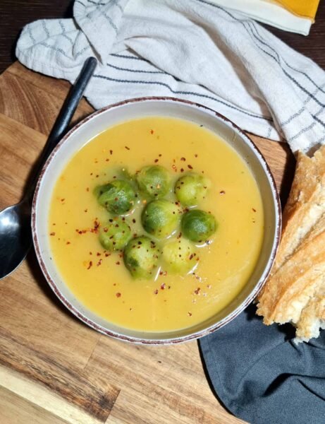 brussels sprouts and potato soup served in a bowl with bread