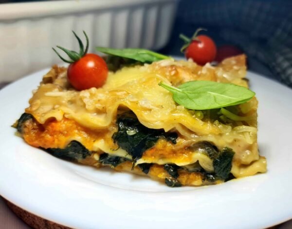 Close-up of a slice showing creamy layers of pumpkin, spinach, and pasta.
