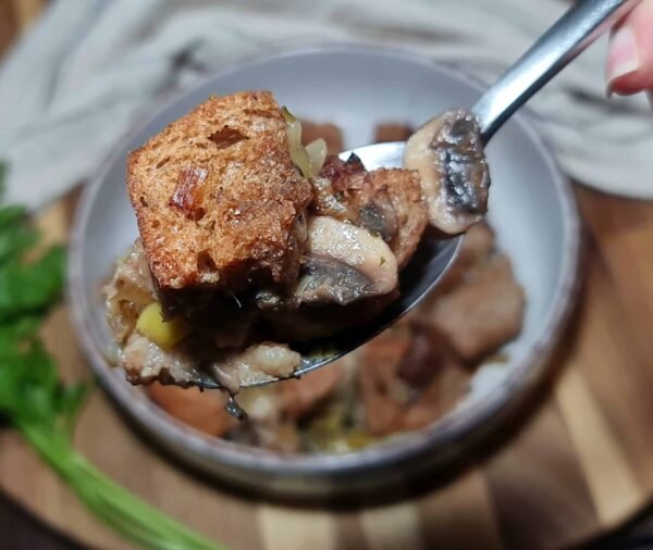 A bowl of homemade vegan stuffing with toasted bread cubes, mushrooms, and celery.