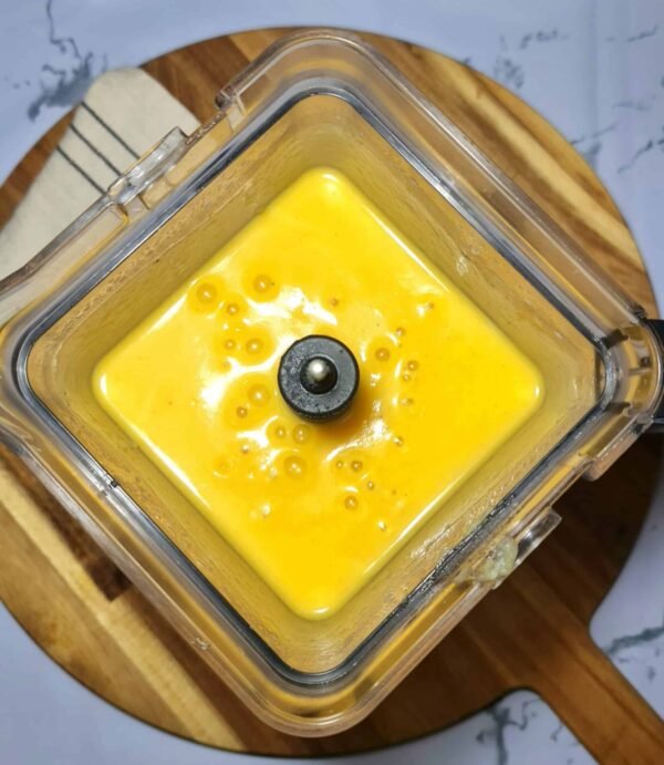 A blender jar filled with smooth, bright yellow-orange winter kohlrabi soup after blending.